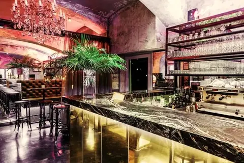 The bar at Thell — brass front, green marble and a chandelier in magenta light