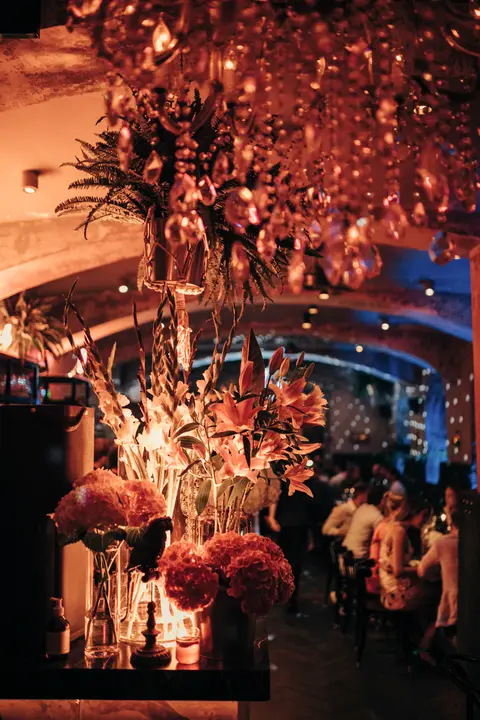 Red-lit bar night with lavish flowers and celebrating guests at Thell