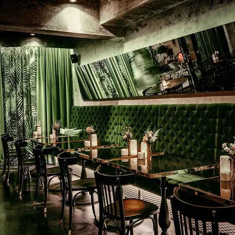 Der grüne Salon im Thell — Samtbänke, Messingtische und Palmenvorhang