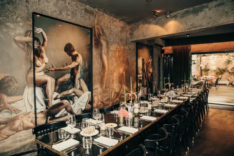 The private dining hall — long table with candles below the large mural